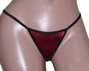 May include: Burgundy satin lingerie with black trim. The lingerie is a thong style with a low rise and a small amount of fabric coverage.