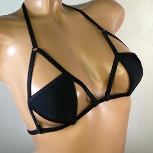 May include: Black lingerie top with a criss-cross strap design and a triangle-shaped cup.