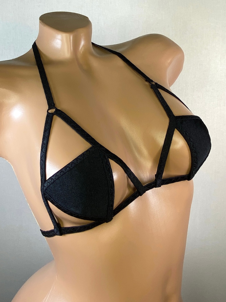 May include: Black lingerie top with a criss-cross strap design and a triangle-shaped cup.