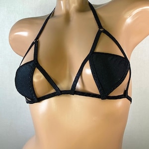 May include: Black lingerie top with a halter strap and a geometric design. The top has a triangle shape in the center and is made of a stretchy fabric.