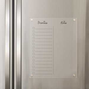 May include: A clear acrylic dry erase board with the words "Priorities" and "Notes" written on it. The board has a checklist on the left side and a blank space on the right side.