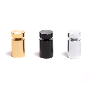 May include: Three metal sign holders in gold, black, and silver. Each holder has a round top and a cylindrical base.