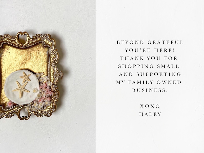 May include: A gold-colored tray with a white ceramic dish featuring two starfish. The tray is decorated with small white and pink flowers. The text on the right side of the image reads: "Beyond grateful you're here! Thank you for shopping small and supporting my family owned business. XOXO Haley."