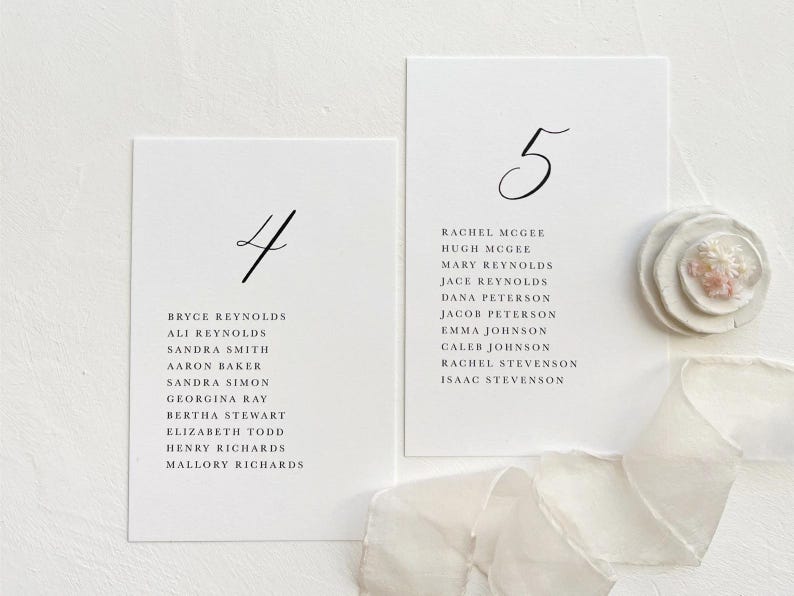 May include: Two white cards with black calligraphy numbers 4 and 5. Each card lists a group of names for a wedding reception seating chart.