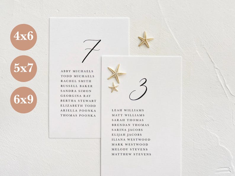 May include: Two white cards with black calligraphy numbers 7 and 3, with gold starfish accents. The cards list names for a wedding reception seating chart.