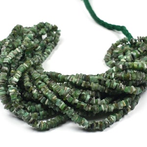 Puede incluir: Un hilo de pequeñas cuentas de piedras preciosas verdes, planas y de forma cuadrada, con variaciones naturales de color que van desde el verde claro hasta el verde bosque oscuro. Las cuentas están ensartadas en un fino cordón verde.