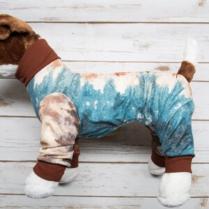 May include: A brown and white stuffed dog wearing a blue and brown tie-dye pajamas with brown trim.
