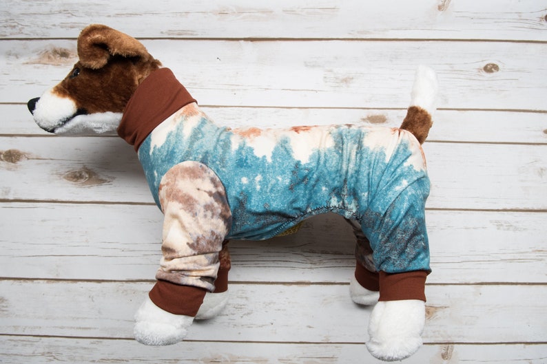 May include: A brown and white stuffed dog wearing a blue and brown tie-dye pajamas with brown trim.