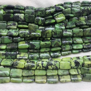 May include: Close-up of square-shaped beads in shades of green and black. The beads have a mottled pattern and are strung together. Ideal for jewellery making, the beads are approximately 1 cm square.