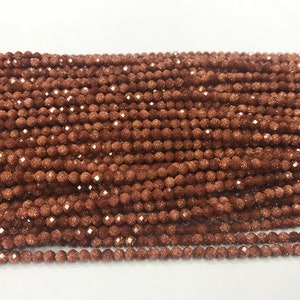 May include: A strand of small, round, faceted, brown gemstone beads. The beads have a sparkly, glittery texture.