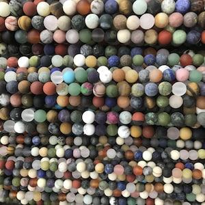 May include: A collection of assorted round gemstone beads in various colors and patterns. The beads are approximately 8mm in diameter and have a matte finish.