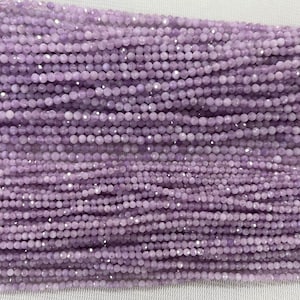 Peut inclure: Un brin de perles de pierres précieuses facettées de couleur lilas clair. Les perles sont petites et rondes, et elles sont enfilées sur un fil transparent.