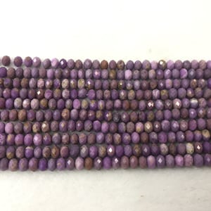 May include: A strand of purple and brown faceted gemstone beads. The beads are small and round, and they are strung together on a clear thread.