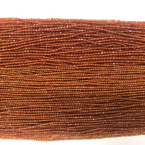 Peut inclure: Un brin de petites perles rondes de couleur brun orangé. Les perles sont facettées et ont un léger éclat.