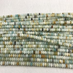 Könnte beinhalten: Eine Strähne runder, glatter, grüner, blauer und brauner Edelsteinperlen. Die Perlen haben einen Durchmesser von etwa 4 mm.