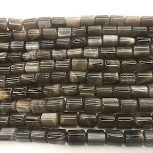 Puede incluir: Una hebra de cuentas de piedra de sol marrón, cada cuenta es un prisma rectangular con un acabado liso y pulido.