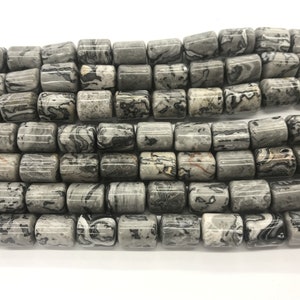 May include: A strand of grey and black patterned stone beads. The beads are cylindrical and have a smooth, polished finish.