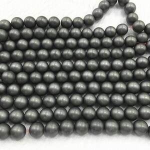 May include: A strand of dark grey round beads. The beads are smooth and have a matte finish.