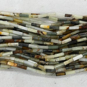 May include: A strand of multi-colored jade beads. The beads are rectangular and have a variety of brown, green, and white patterns.