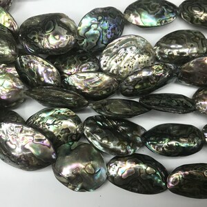 以下が含まれることがあります： 緑、青、紫の虹色に輝く、楕円形の真珠貝のビーズのストランド。ビーズは滑らかで磨かれており、自然で有機的な質感です。