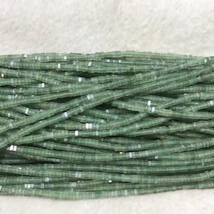 Puede incluir: Una hebra de cuentas cuadradas de vidrio verde claro. Las cuentas son translúcidas y tienen un acabado ligeramente iridiscente.