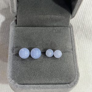 May include: Four light blue agate gemstone earrings in a gray velvet jewelry box. The earrings are in two different sizes.