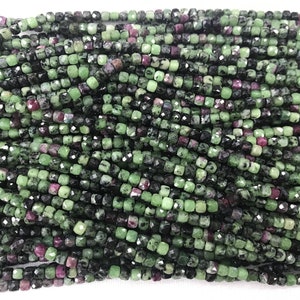 May include: A strand of green, black, and pink gemstone beads. The beads are faceted and have a square shape.