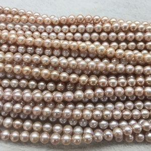 May include: A strand of light pink freshwater pearls. The pearls are round and smooth, and they have a subtle iridescent sheen.