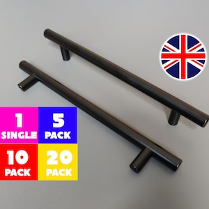 May include: Two black T-bar cabinet handles. The image shows the handles against a grey background, with text indicating pack sizes of 1, 5, 10, and 20. A British flag emblem is also visible.