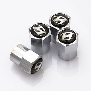 May include: Set of four silver tyre valve stem caps with a black background and a silver Hyundai logo.