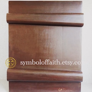 May include: A dark brown wooden icon board with a rounded edge and a gold symbol of faith in the top left corner. The text "symboloffaith.etsy.co" is printed in white on the board. The board is signed "Lyttle S. January 2019" in the bottom right corner.