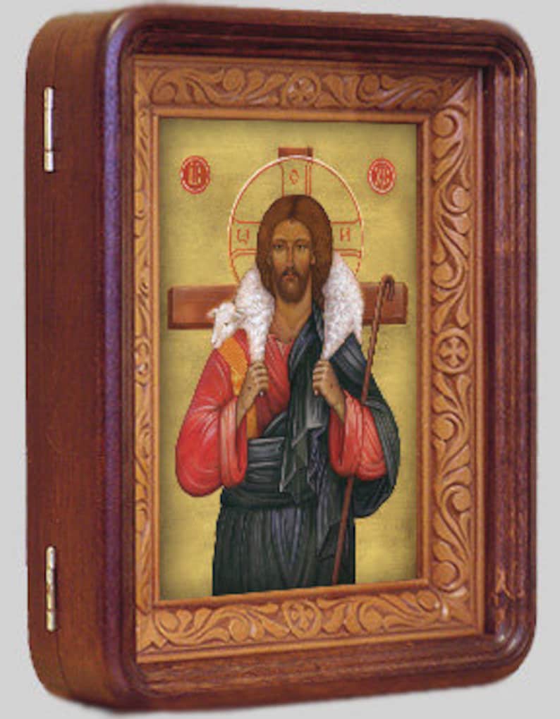 May include: A religious icon depicting Jesus Christ as the Good Shepherd, carrying a lamb on his shoulders. He is wearing a red robe and a blue tunic, and holding a shepherd's staff. The icon is framed in a wooden frame with intricate carvings.