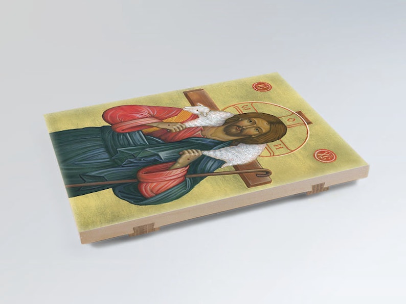 May include: A religious icon depicting Jesus Christ as the Good Shepherd. He is carrying a lamb on his shoulders and holding a staff. The icon is painted in a traditional style with vibrant colours and gold accents.