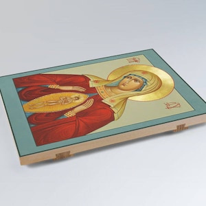 May include: A religious icon depicting the Virgin Mary in a red robe with gold trim, holding a small figure of Jesus in her arms. The icon is painted on a wooden panel with a blue and gold background.