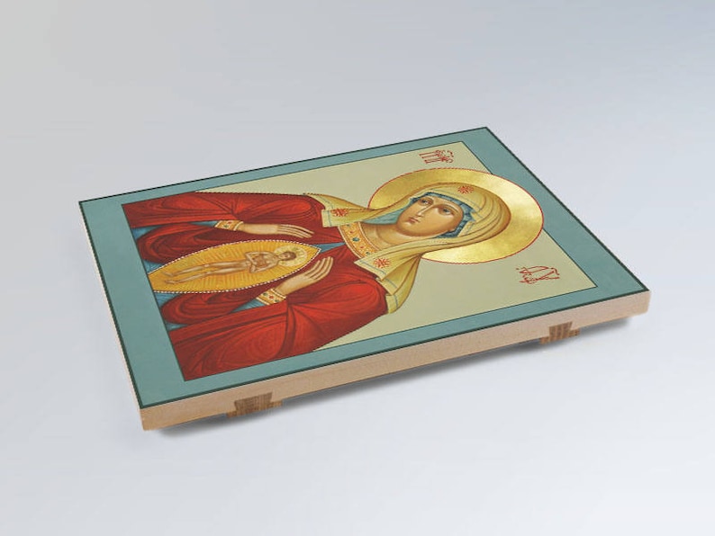 May include: A religious icon depicting the Virgin Mary in a red robe with gold trim, holding a small figure of Jesus in her arms. The icon is painted on a wooden panel with a blue and gold background.