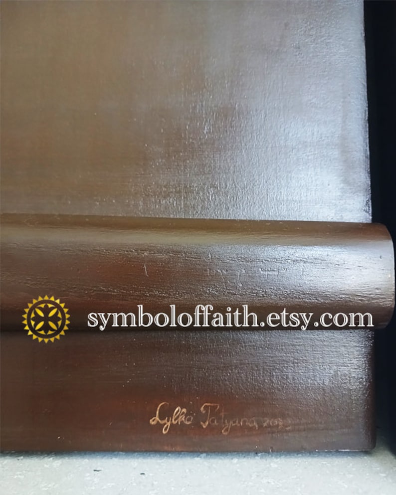 May include: A dark brown wooden frame with a gold star and the text "symboloffaith.etsy.com". The frame is signed "Lylia Tatiana 202".