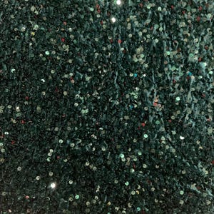 Peut inclure: Gros plan sur un tissu vert foncé recouvert de petites paillettes rondes. Les paillettes réfléchissent la lumière, créant un effet scintillant. Le tissu a un aspect doux et texturé, adapté aux vêtements ou aux projets décoratifs.