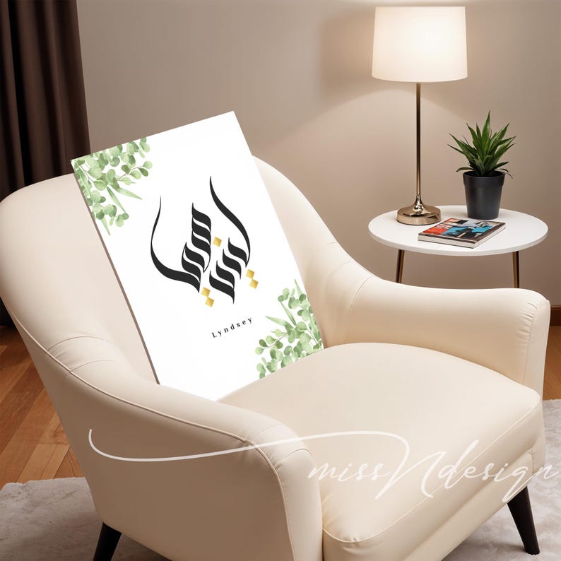 Puede incluir: Una impresi&oacute;n art&iacute;stica blanca con un dise&ntilde;o negro estilizado con detalles dorados y el nombre "Lyndsey". La impresi&oacute;n est&aacute; adornada con hojas verdes de acuarela y se muestra en un sill&oacute;n color crema.