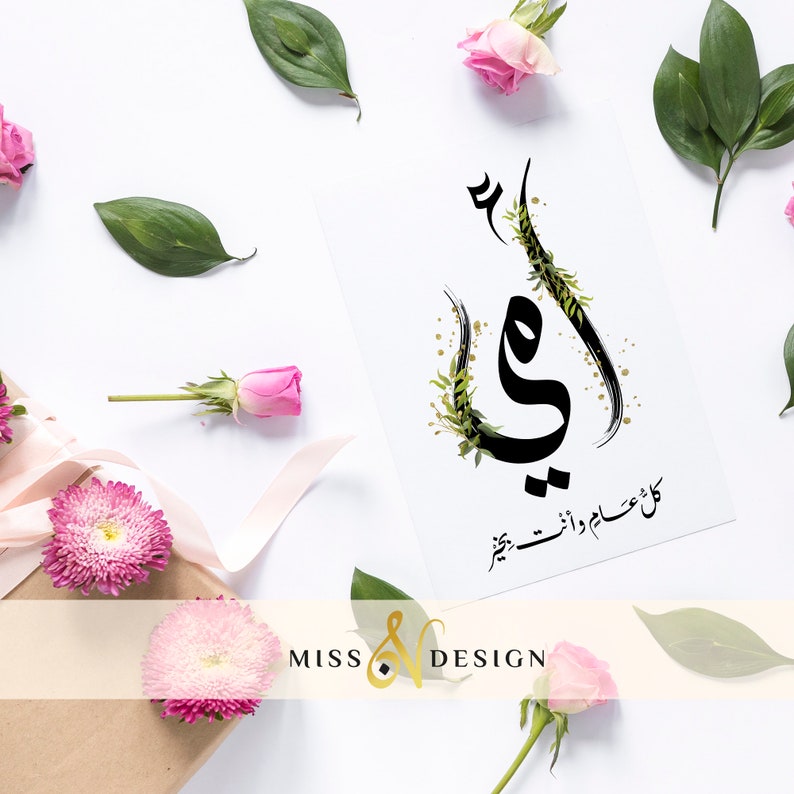 May include: A white card with black calligraphy that says "Mom" in Arabic. The card is decorated with green leaves and gold glitter. The card is surrounded by pink roses and green leaves.