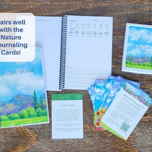 May include: A collection of nature journaling supplies, including a spiral-bound journal with a landscape illustration, a set of activity cards, and a notebook with weather and notes sections. The text "Pairs well with the Nature Journaling Cards!" is visible.