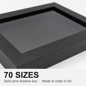 May include: A black shadow box frame constructed from solid pine with a deep interior display area and a clear glass front. The text 70 SIZES Solid pine shadow box · Made to order in NJ is printed below the frame on a white background.