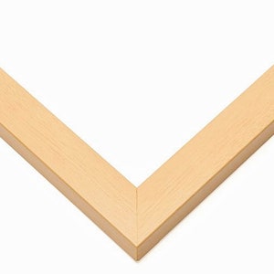 May include: A close-up of a corner of a light wood picture frame.