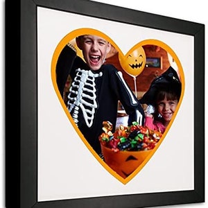 May include: Two children dressed in Halloween costumes, one in a skeleton costume and the other in a witch costume, are holding a bucket of candy. The image is in a heart shape with an orange border.