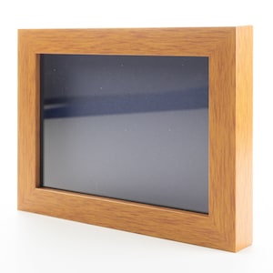 May include: A wooden picture frame with a dark gray mat and a light wood finish.