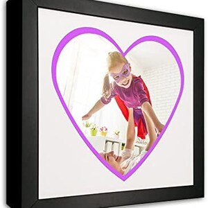 May include: A black picture frame with a white mat and a purple heart-shaped outline around a photo of a child wearing a purple superhero costume and a mask, flying through the air while being held by an adult.