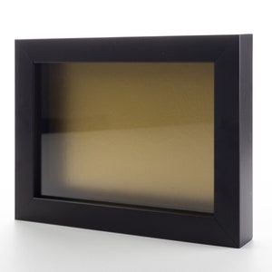 May include: Black picture frame with a clear glass front and a gold-colored mat.