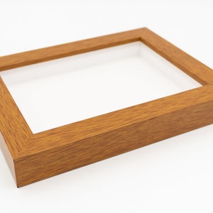 May include: A wooden picture frame with a light brown finish. The frame is empty and has a glass front.