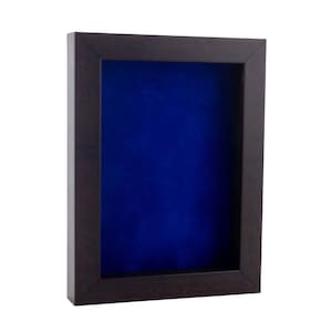 May include: A dark brown wooden shadow box with a blue velvet interior. The box has a simple design and is perfect for displaying small items.