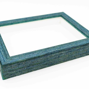 May include: A teal blue picture frame with a wood grain finish. The frame is empty and ready to display a photo or artwork.