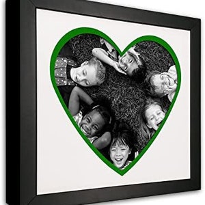 May include: Black and white photo of five children lying in a grassy field, their heads forming a heart shape with a green outline. The children are smiling and looking at the camera.